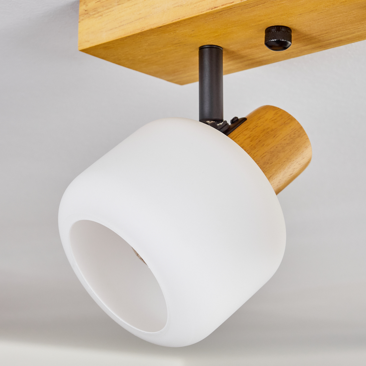 Eine Deckenleuchte mit weißer Lampe und Holzakzenten. Das Licht ist gegen einen weißen Hintergrund nach unten gerichtet.