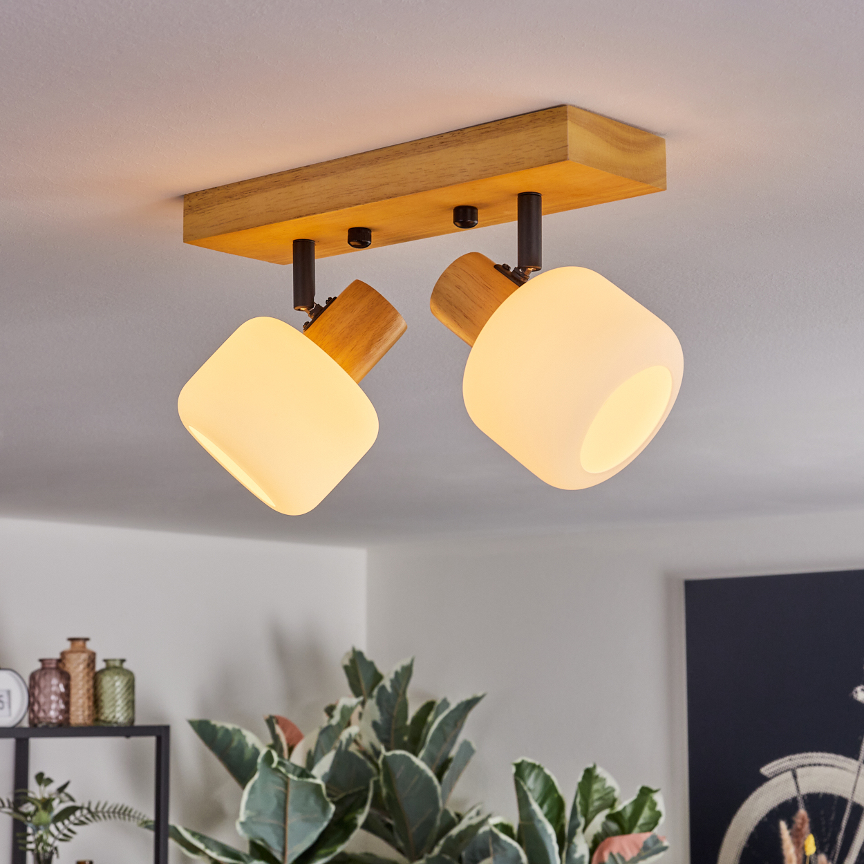 Deckenleuchte mit zwei leuchtenden Lampen. Holzsockel und Lampenschirme. Pflanzen im Hintergrund, Bild mit Fahrrad.