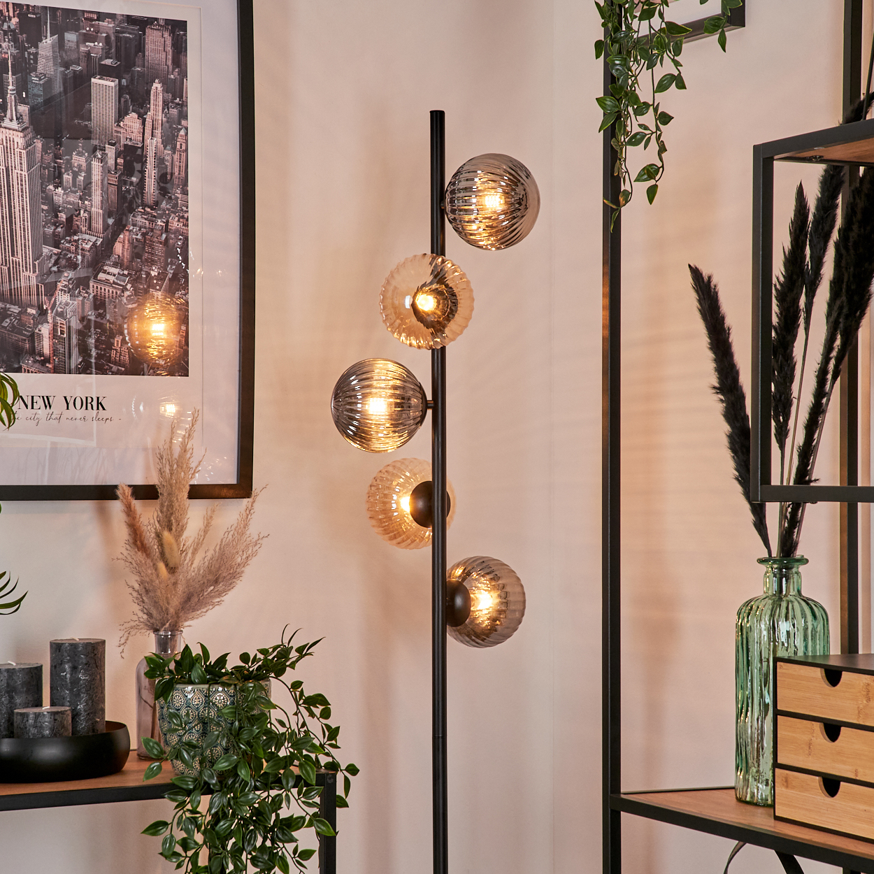 Eine moderne Stehlampe mit Kugelschirmen. Ein gerahmtes New York-Bild, Pflanzen, Kerzen und Regale sind ebenfalls sichtbar.