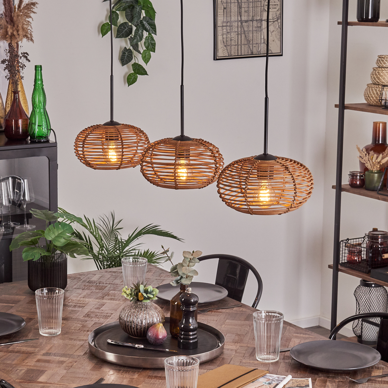 Ein Esszimmer mit Holztisch, drei Pendelleuchten und Regal. Tisch mit Tablett, Gläsern und Tellern.