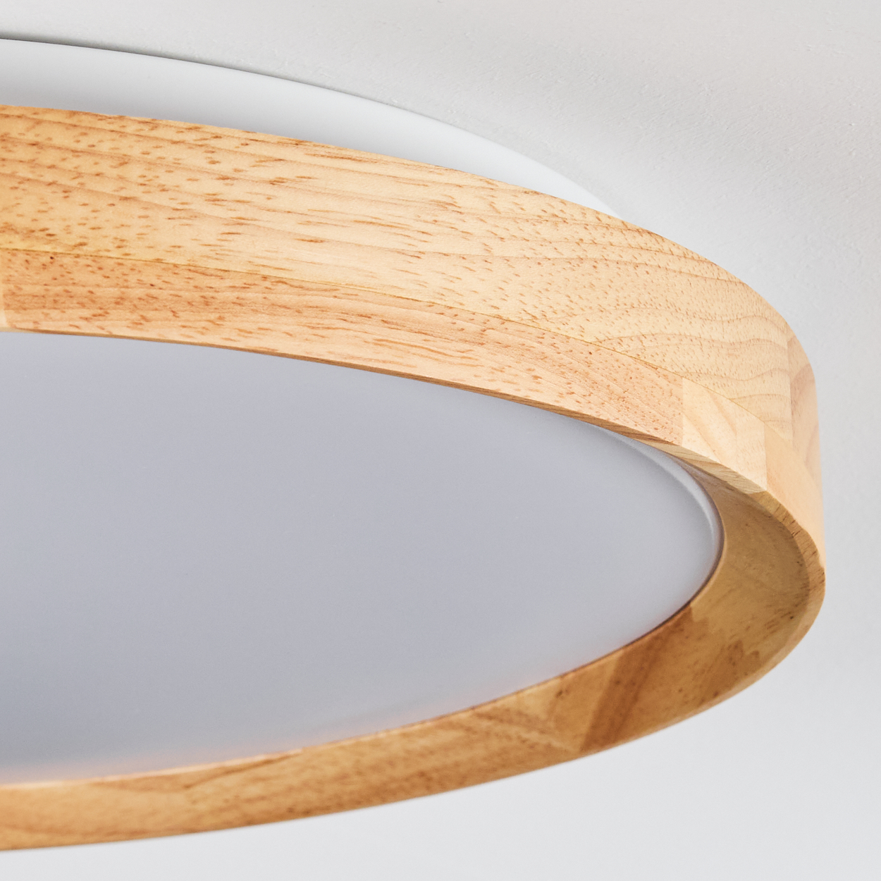 Nahaufnahme einer Deckenleuchte aus Holz. Sie hat einen Rahmen aus hellem Holz und eine weiße und mattierte Glasscheibe.