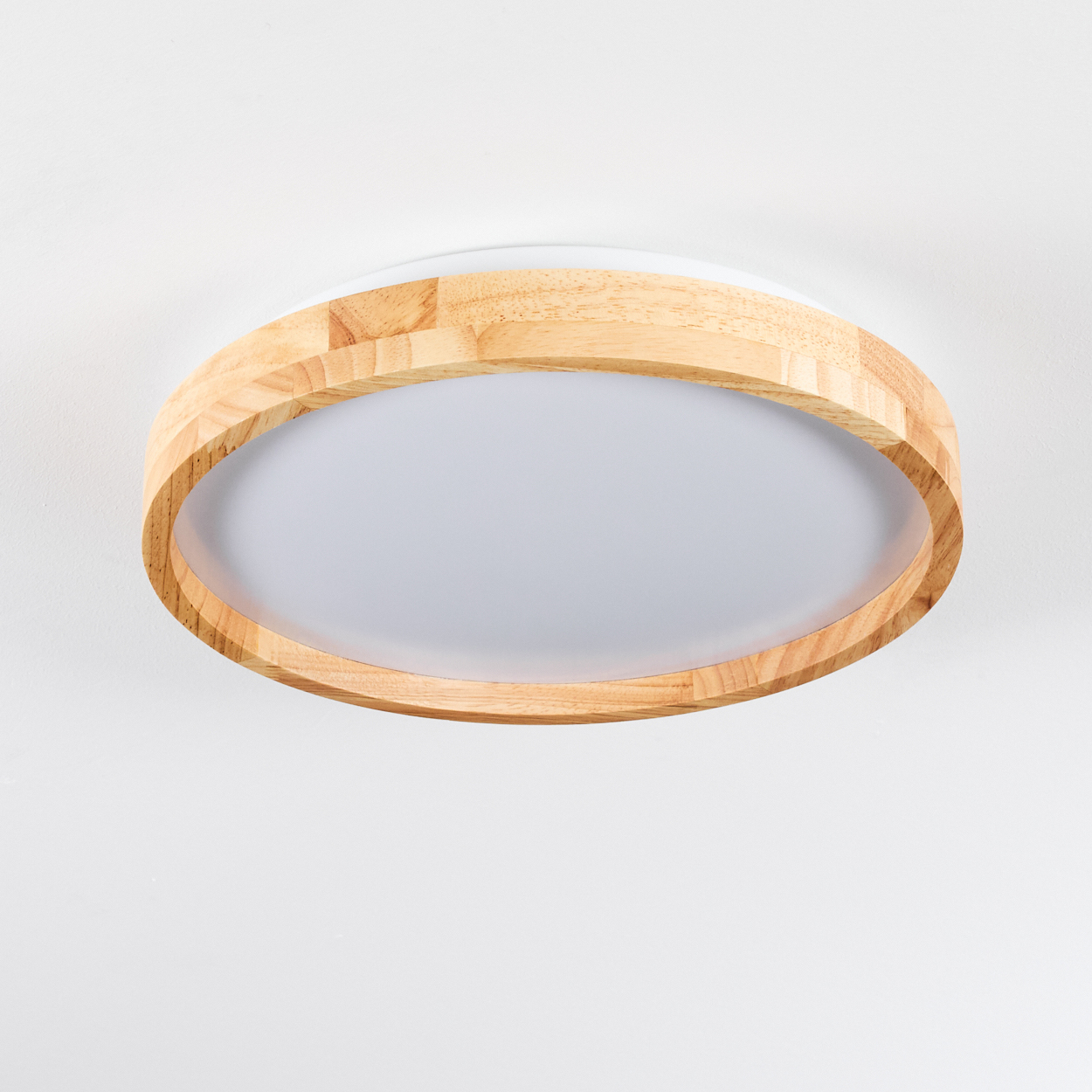 Eine runde Deckenlampe mit Holzrahmen und weißem Diffusor. Sie ist an einer weißen Decke befestigt.