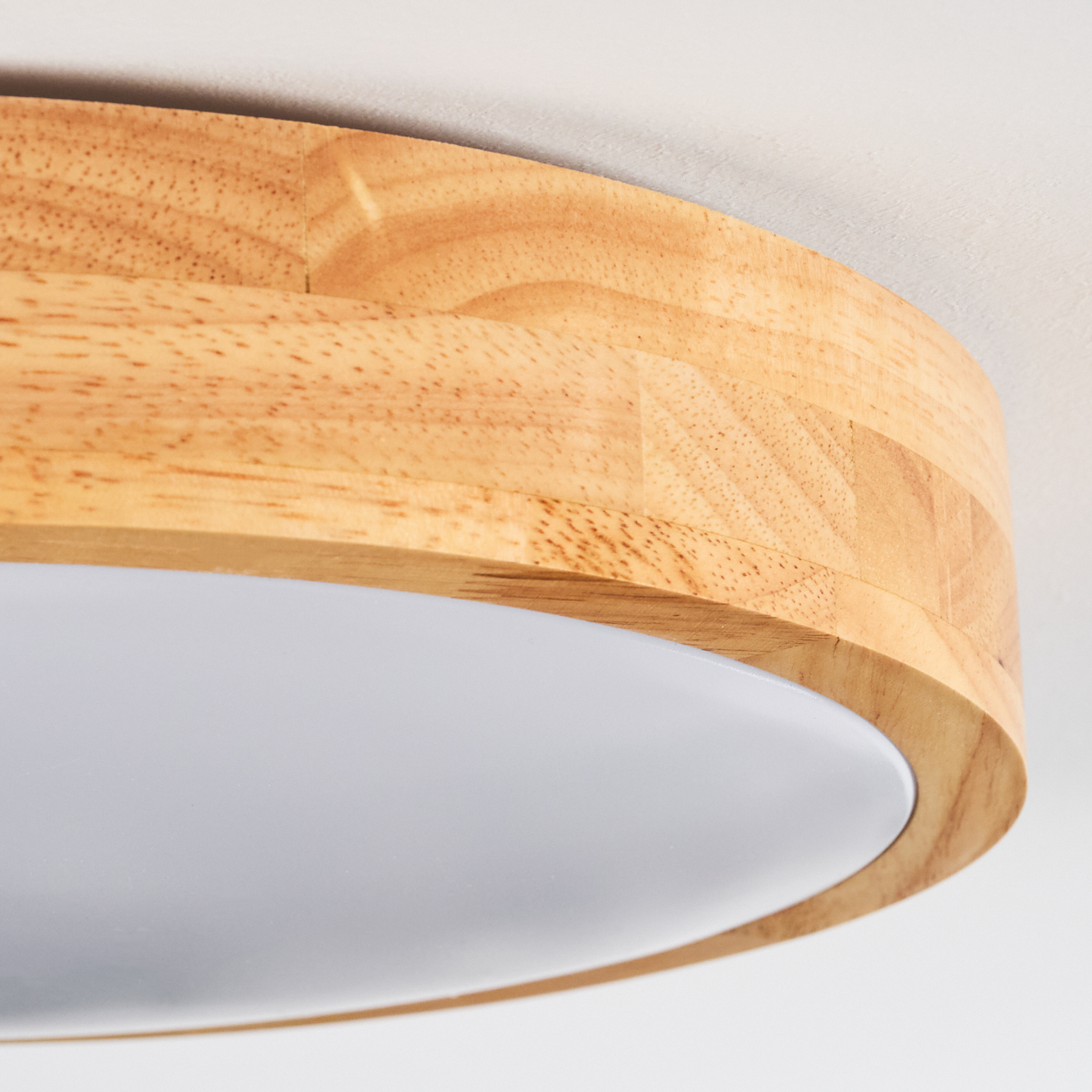 Nahaufnahme einer Deckenlampe aus Holz. Die Lampe hat einen hellen Holzrahmen und eine weiße, diffuse Lichtplatte. Der Hintergrund ist weiß.