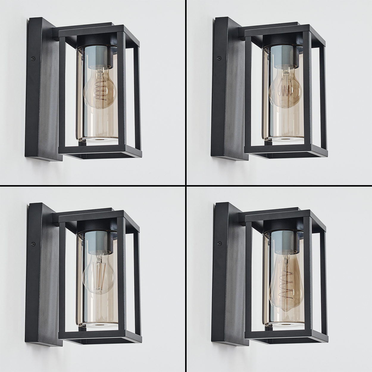 Vier schwarze Wandlampen mit rechteckigen Rahmen und Glaszylindern mit Glühbirnen im Inneren, an einer weißen Wand montiert.