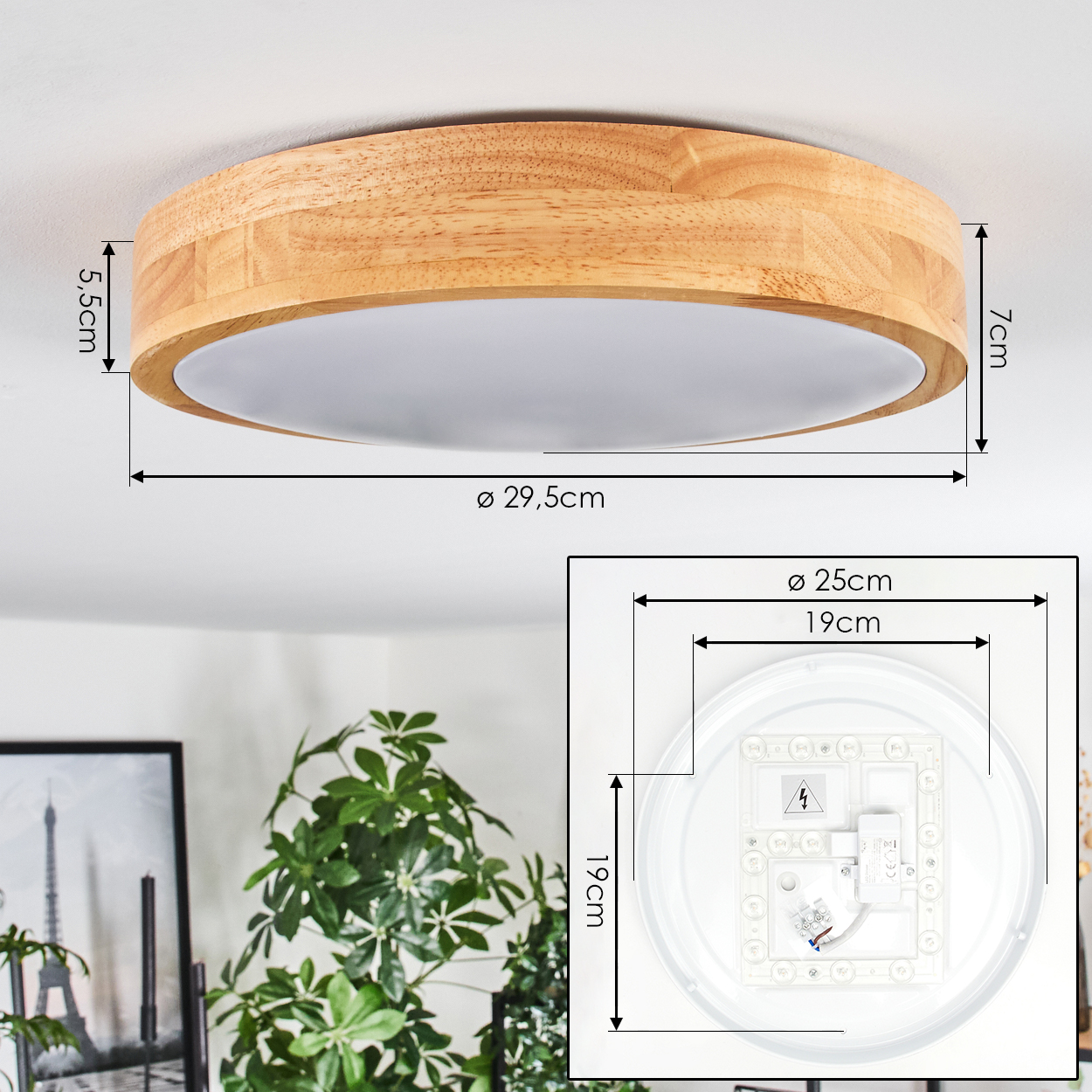 Eine runde Deckenlampe aus Holz mit Maßen. Unter dem Holzrahmen befindet sich eine weiße Lichtplatte. Pflanzen und ein gerahmtes Bild im Hintergrund.