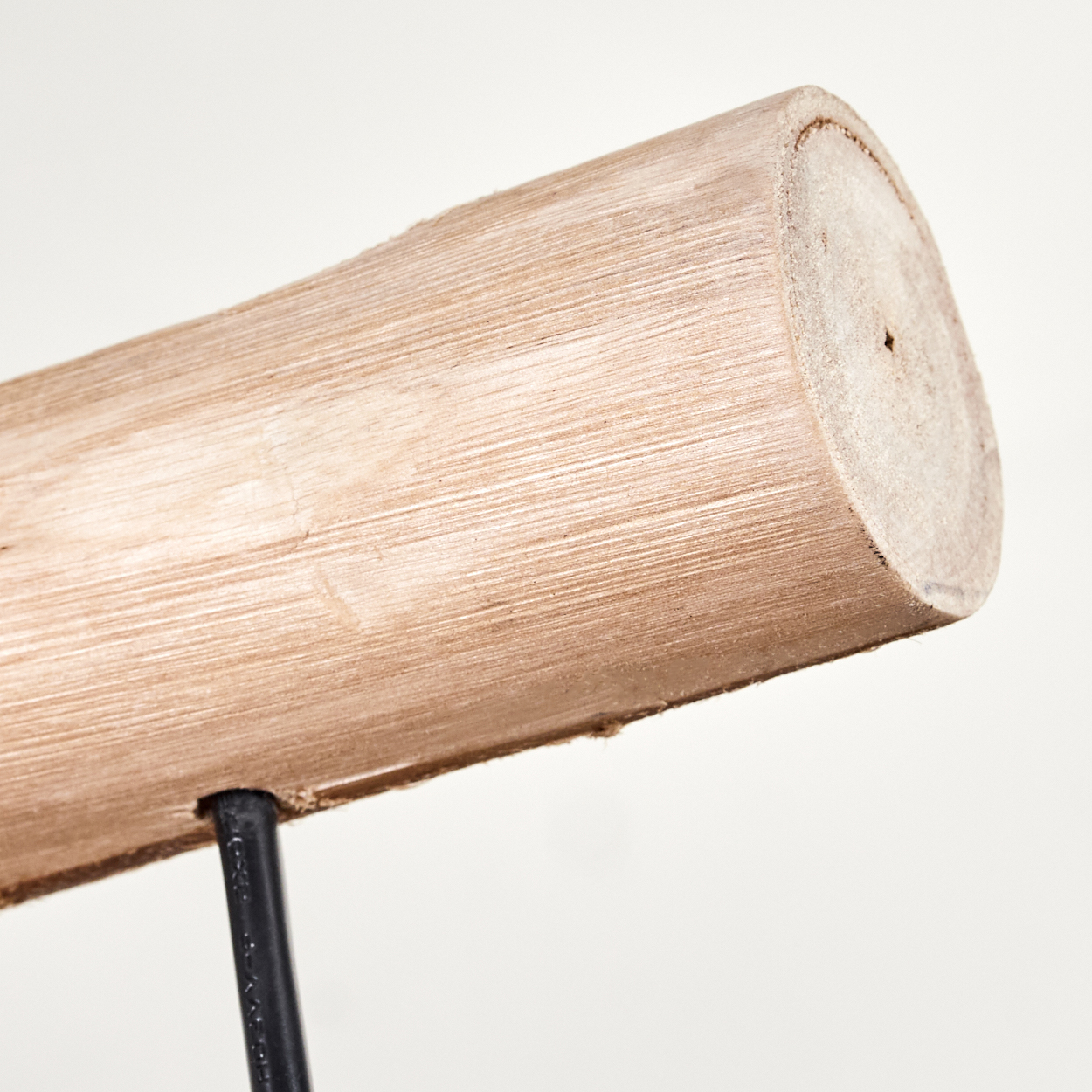 Nahaufnahme eines Holzstamms mit sichtbarer Maserung, gestützt von einem schwarzen Metallbein, vor weißem Hintergrund.