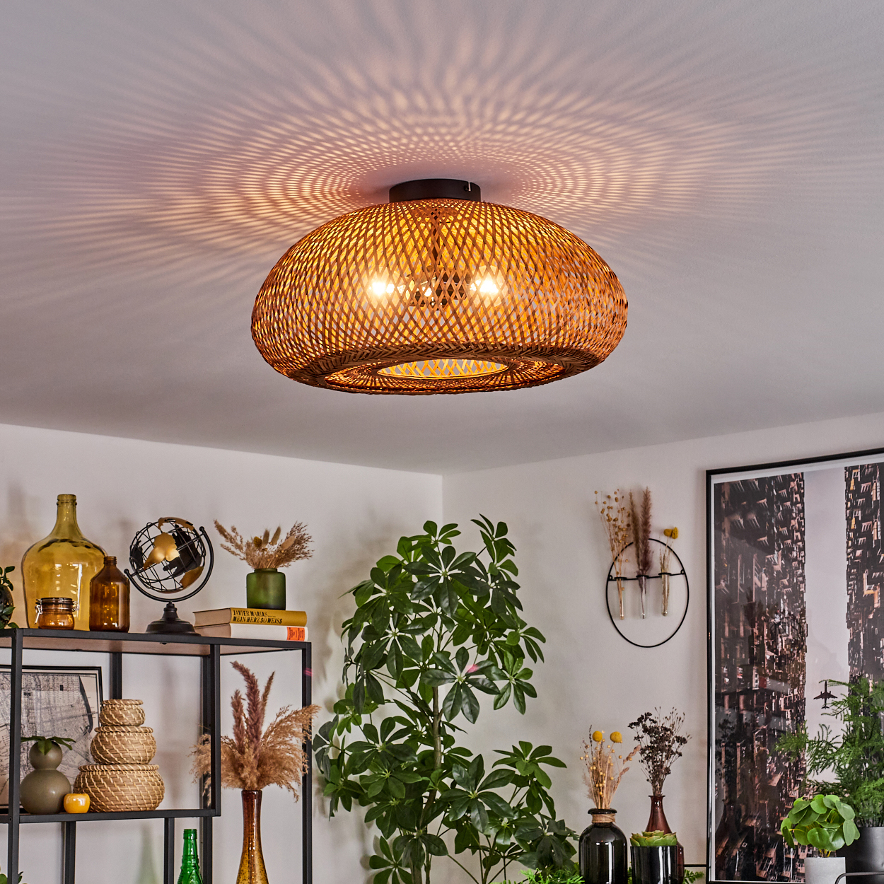 Eine gewebte Lampe hängt von der Decke und wirft Musterlicht. Darunter ein Regal mit Dekor, Pflanzen und einem Globus, mit einem gerahmten Bild an der Wand.
