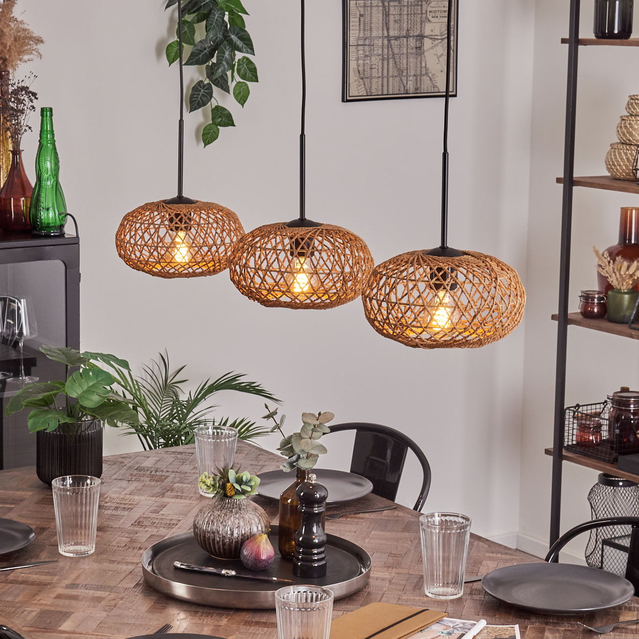 Ein Esszimmer mit drei gewebten Pendelleuchten über einem Holztisch, der für eine Mahlzeit gedeckt ist, mit Pflanzen und Dekoration.