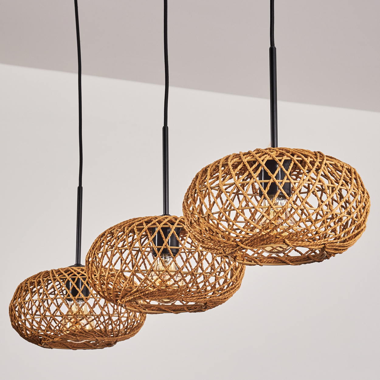 Drei gewebte Lampen hängen von der Decke. Die Lampenschirme sind braun und kreisförmig, mit schwarzen Kabeln und Armaturen.