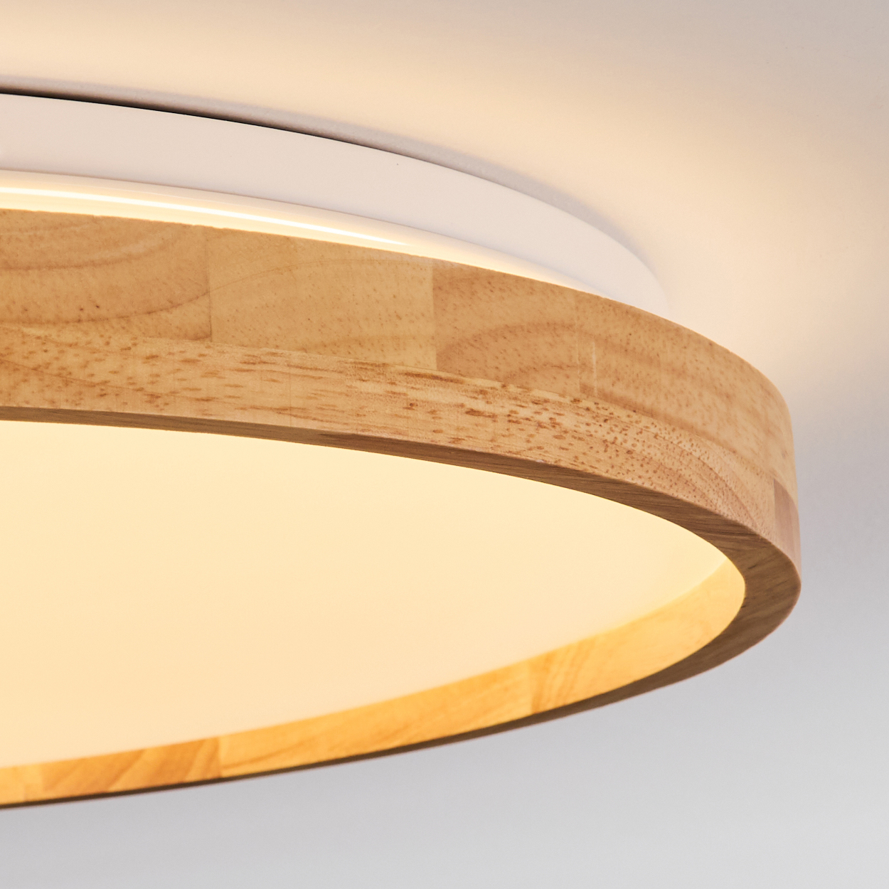 Nahaufnahme einer Deckenleuchte aus Holz und Weiß. Das Licht ist an und der Holzteil hat eine warme, natürliche Farbe.