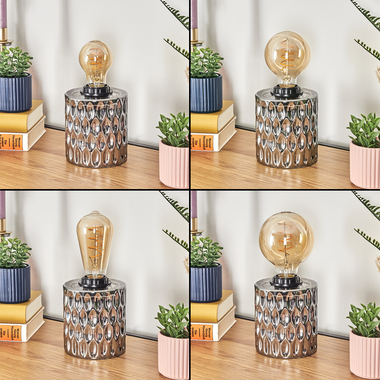 Eine dekorative Lampe mit silbernem Sockel und großer Glühbirne. Auf einer Holzoberfläche stehen kleine Topfpflanzen und Bücher.