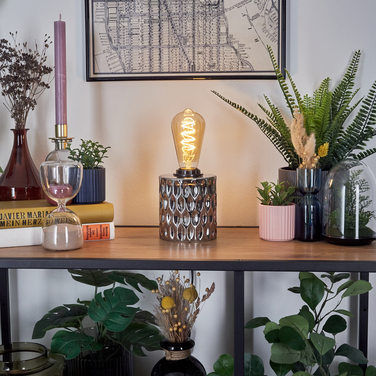 Ein Regal zeigt eine Lampe, Pflanzen, Bücher und Dekorationen. Eine Karte hängt oben. Die Szene ist gut beleuchtet.