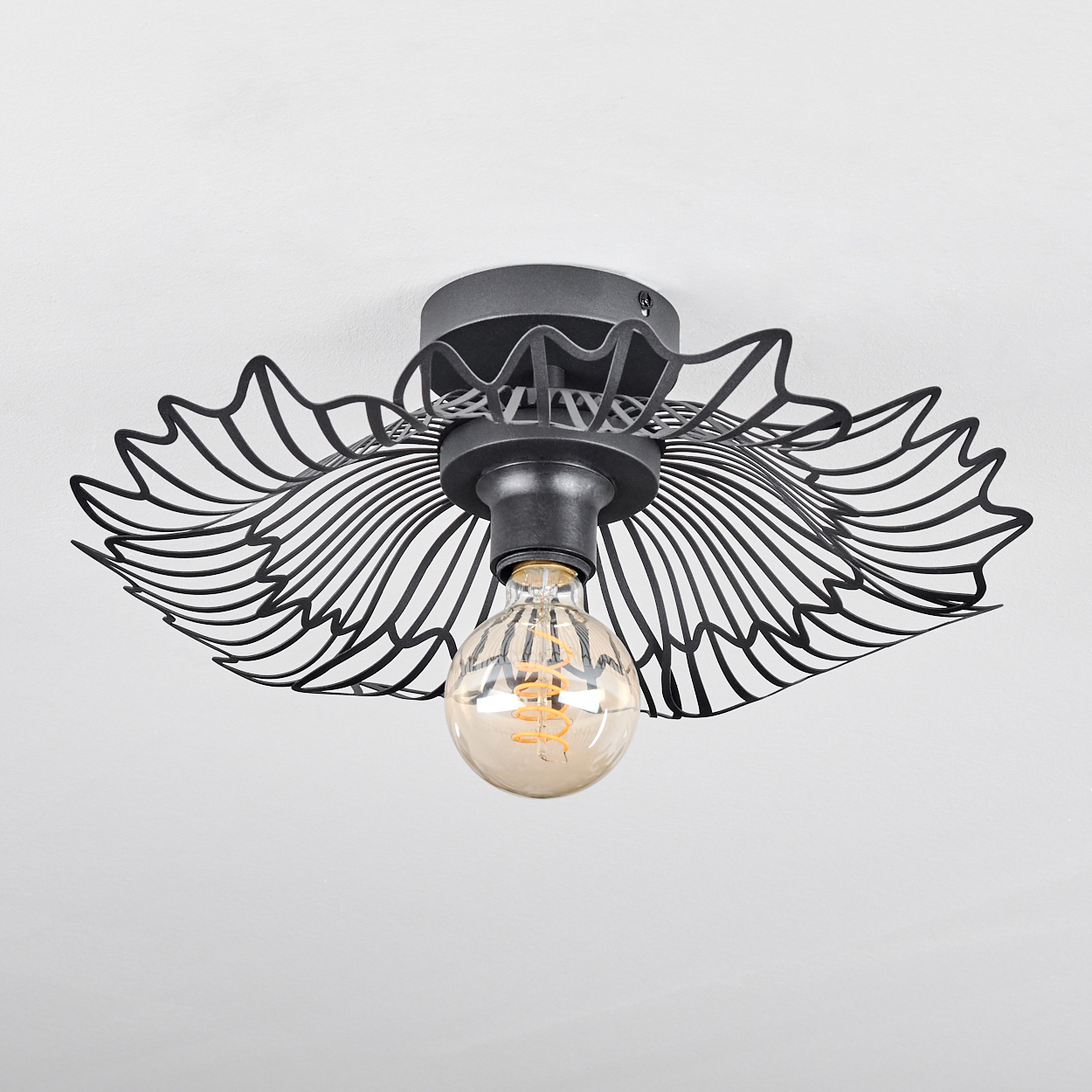 Deckenleuchte mit schwarzem Metallrahmen im Flügeldesign. In der Mitte befindet sich eine Glühbirne, die Decke ist weiß.