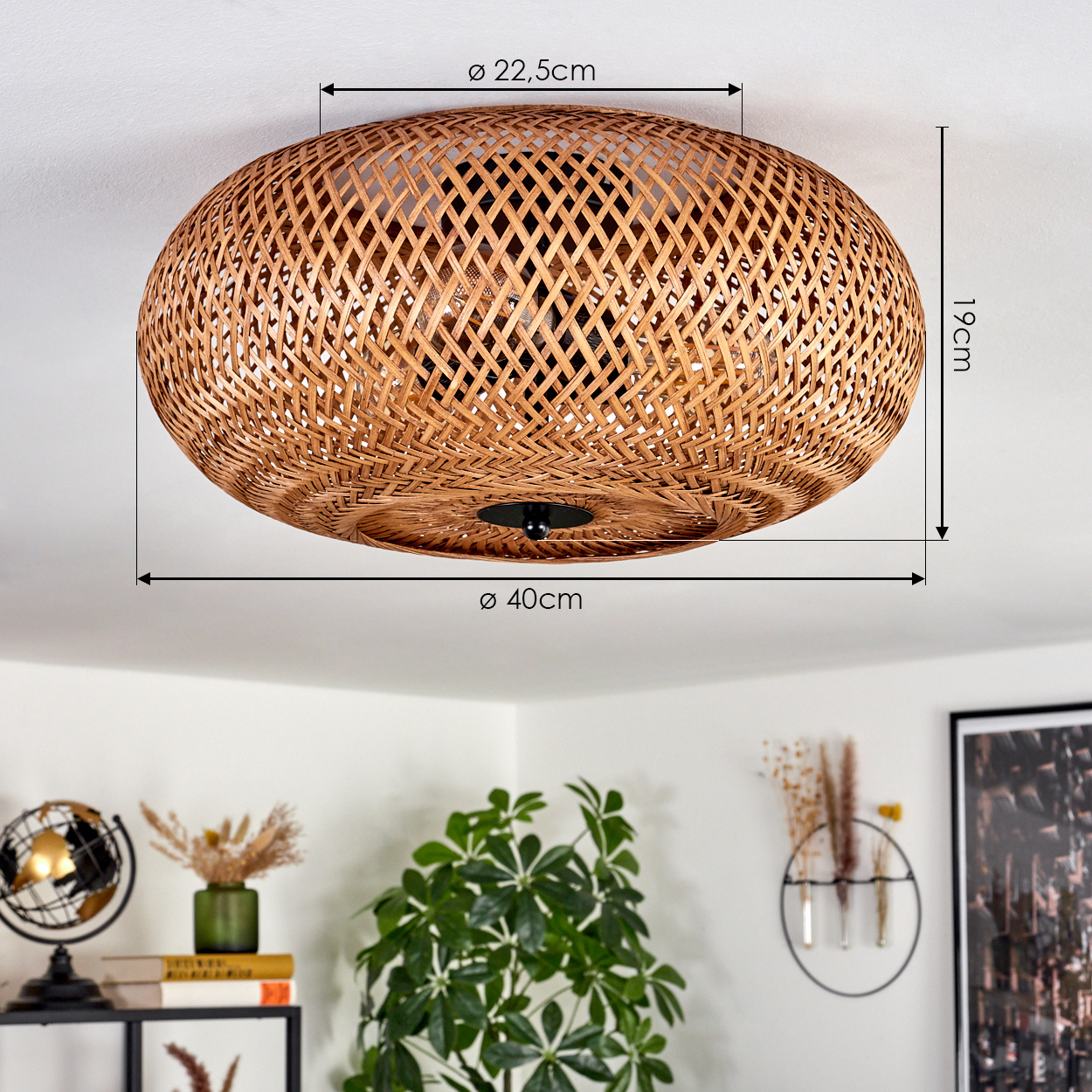 Eine Deckenlampe aus gewebtem Rattan mit Abmessungen wird gezeigt. Darunter sind eine grüne Pflanze, ein Globus, Bücher und Dekor zu sehen.