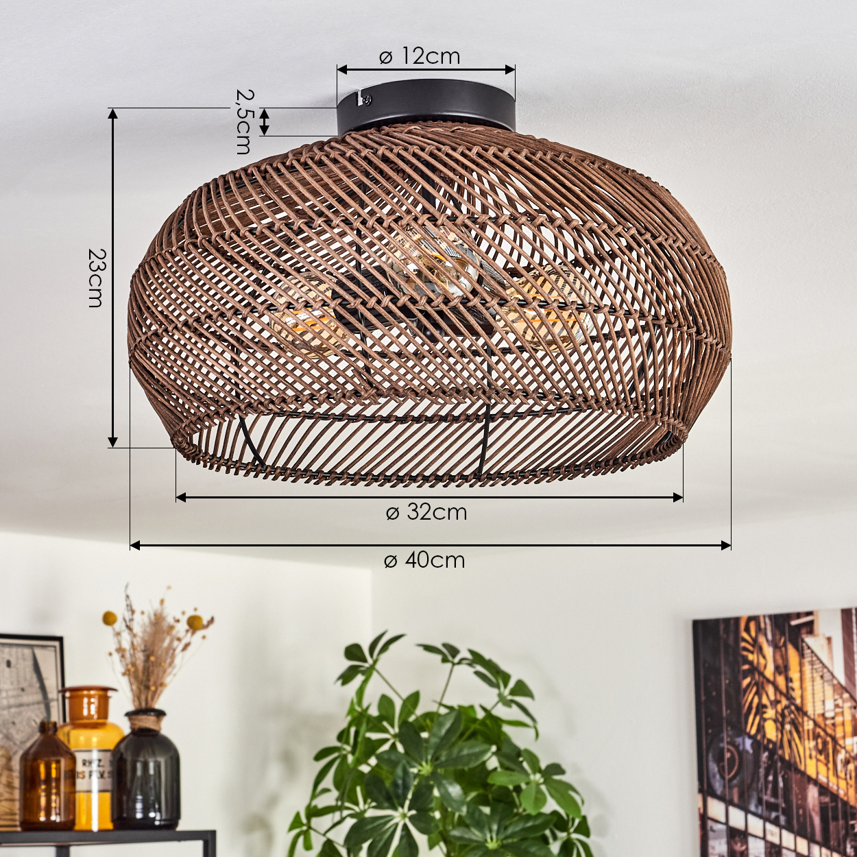 Eine braune, geflochtene Deckenleuchte aus Rattan mit Maßangaben. Darunter Vasen, eine Pflanze und ein gerahmtes Bild.