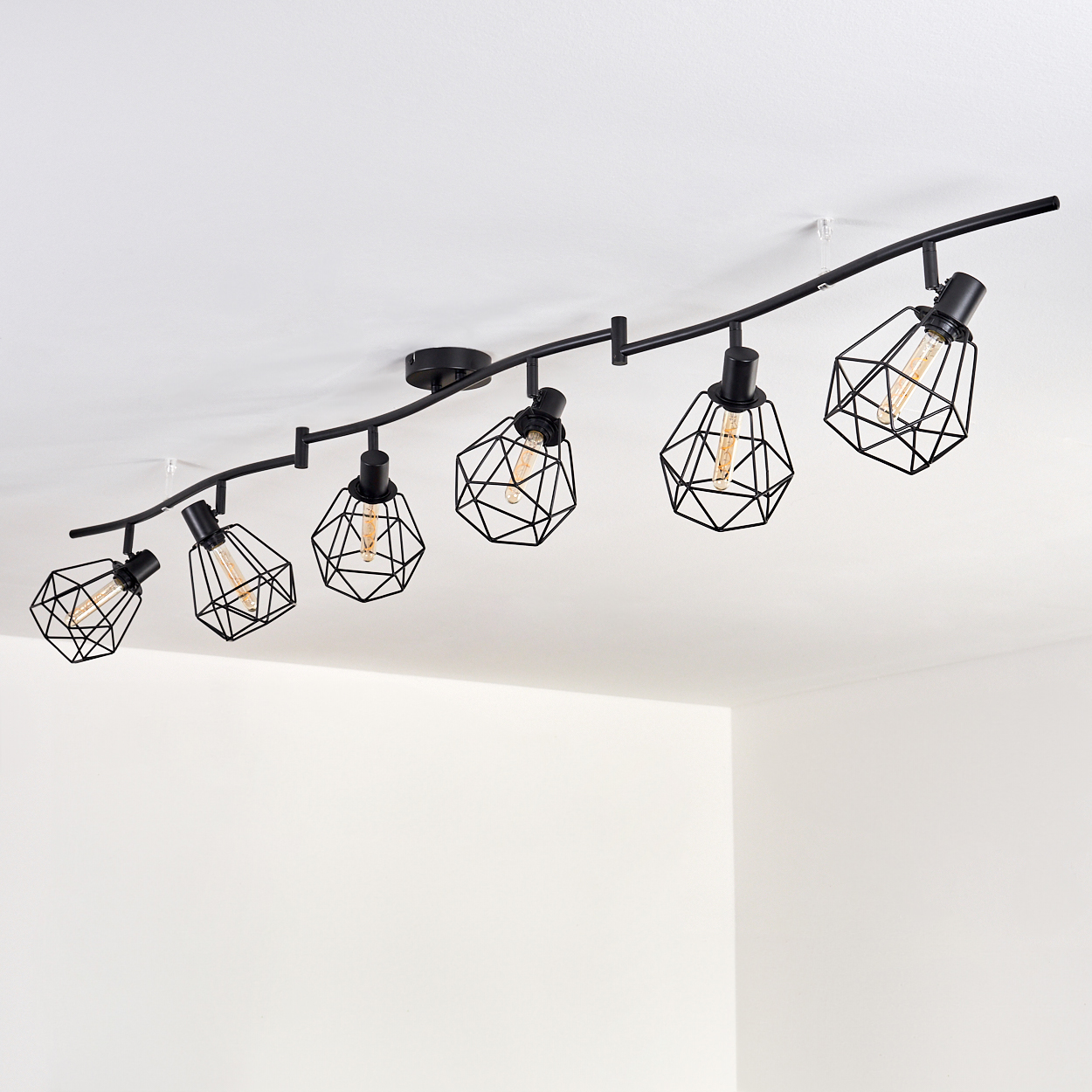 Schwarze Schienenbeleuchtung mit sechs geometrischen Lampen im Käfigstil, an einer weißen Decke montiert.