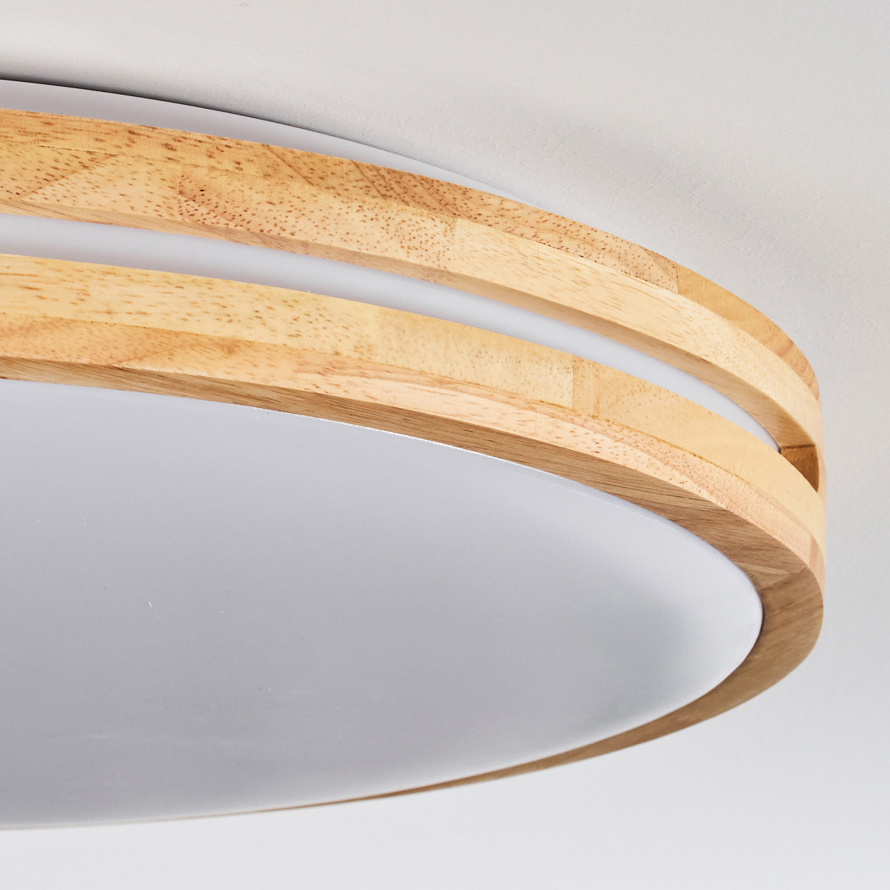 Eine moderne Deckenleuchte mit gebogenem Holzrahmen und weißem, ovalem Diffusor. Der Hintergrund ist schlicht weiß.