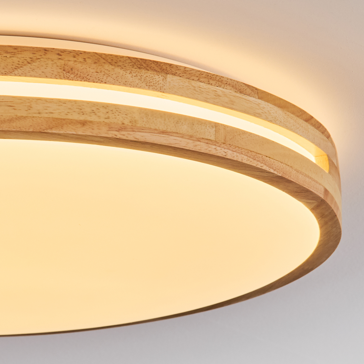 Nahaufnahme einer Deckenleuchte aus Holz. Das Licht hat ein kreisförmiges Design mit warmem, diffusem Glanz. Das Holz hat eine natürliche, helle Farbe.