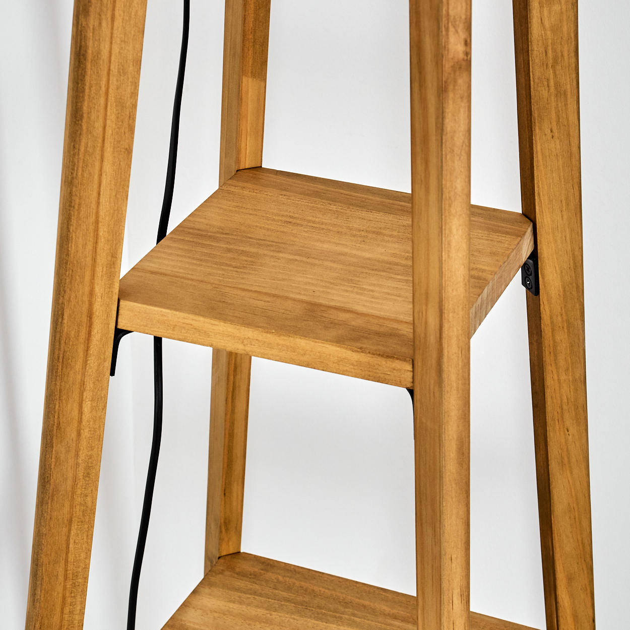 Holzregal mit drei Ebenen. Schwarzes Kabel verläuft an der Seite. Hellbraunes Holz vor weißem Hintergrund.