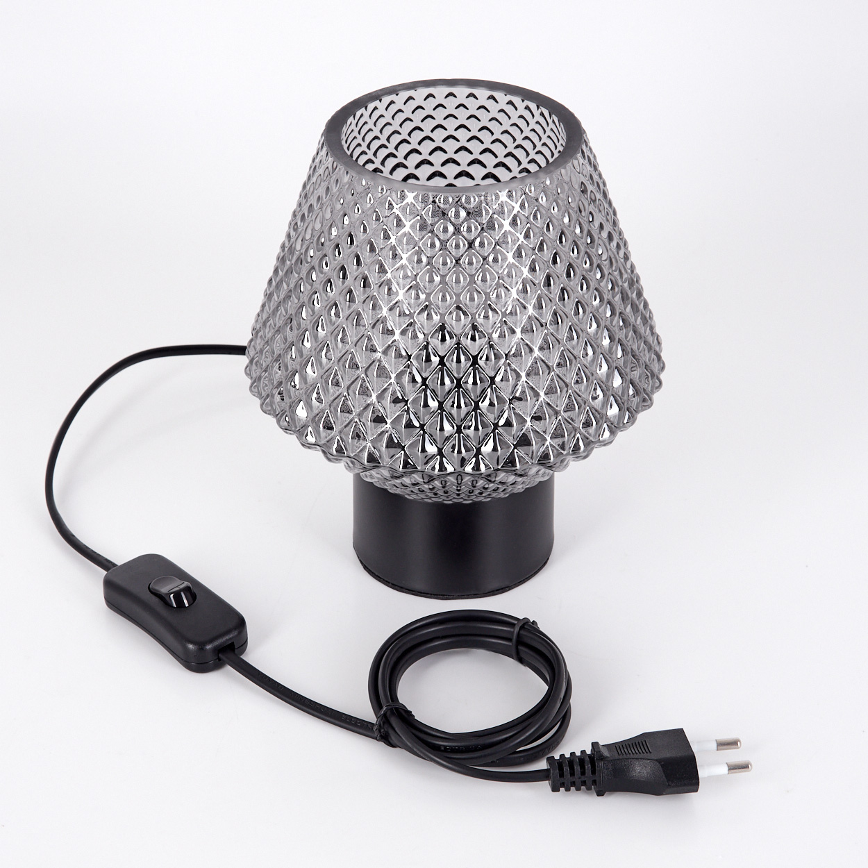 Eine kleine, dekorative Lampe mit strukturiertem Glasschirm steht auf einem schwarzen Sockel. Sie hat ein schwarzes Kabel mit Schalter und Stecker.