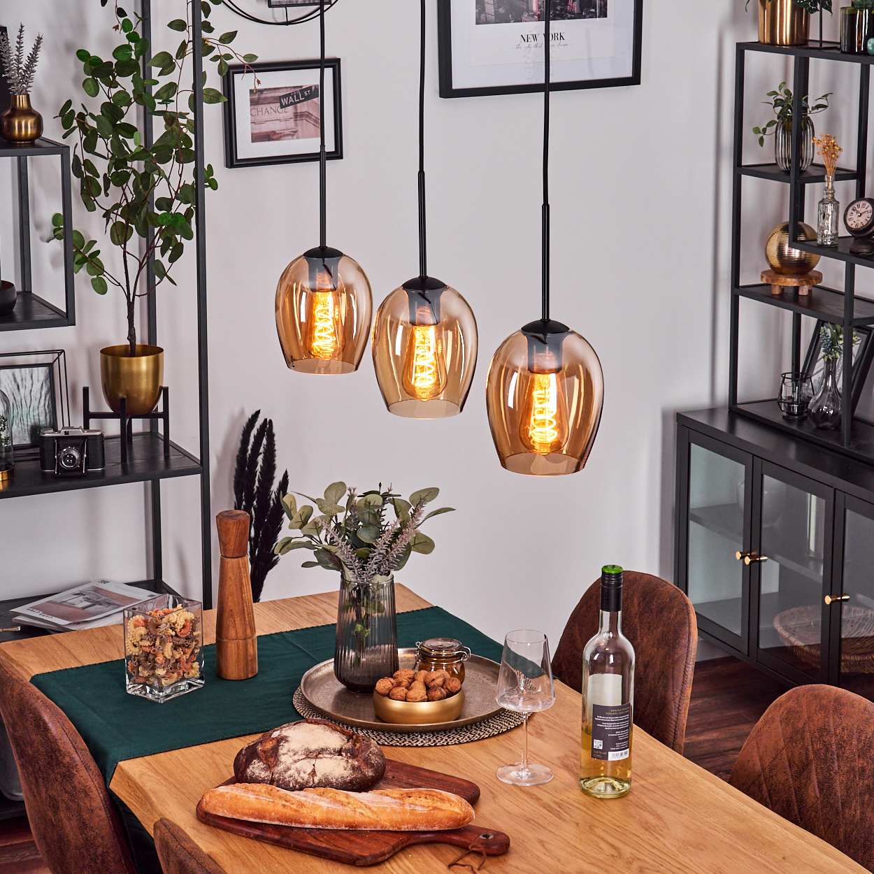 Esszimmer mit Hängelampen, einem Holztisch für das Abendessen. Brot, Wein und Dekorationsartikel sind sichtbar.