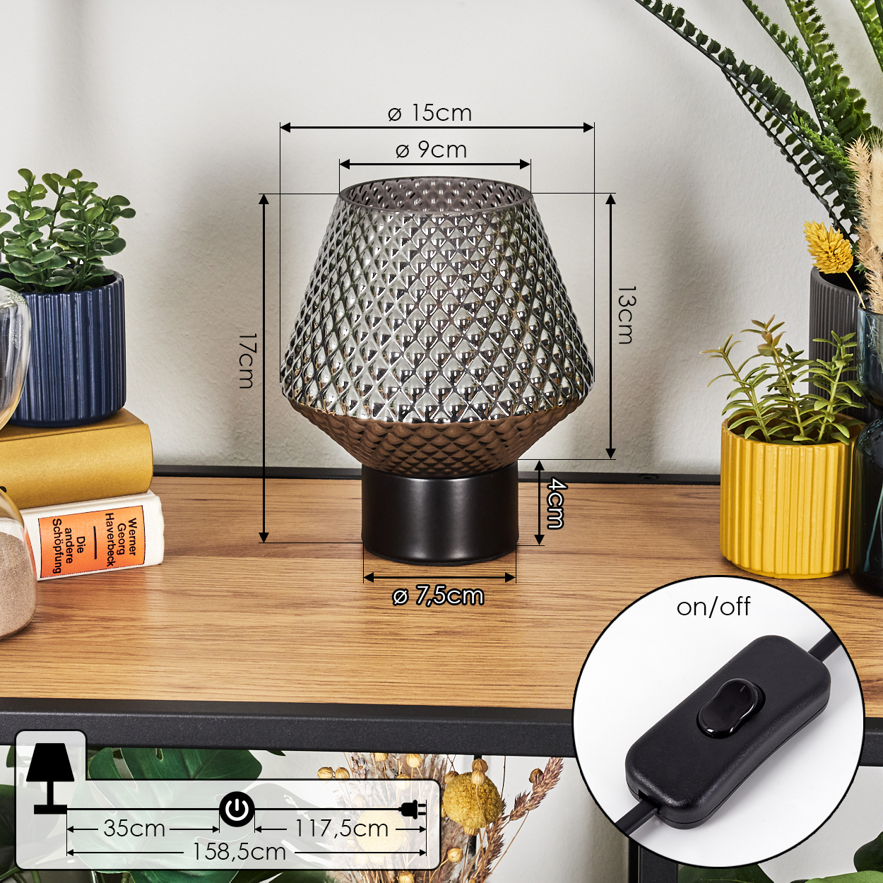 Eine dekorative Lampe mit strukturiertem Schirm steht auf einer Holzoberfläche. Weitere Elemente sind Pflanzen und ein Schalter. Maße sind angegeben.