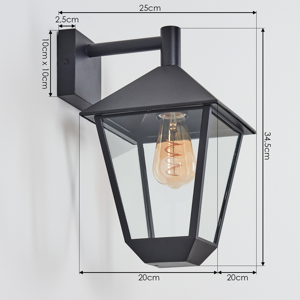 Schwarze Außenlampe mit Maßangaben. Enthält Glasscheiben und eine sichtbare Glühbirne. An einer weißen Wand montiert.