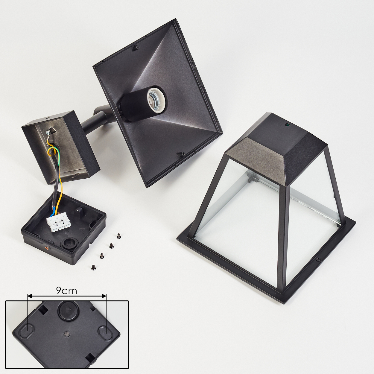 Zerlegte schwarze Außenlampenteile auf weißer Oberfläche. Enthält Lampengehäuse, Glasschirm, Elektrokasten und Schrauben. 9cm Messung.
