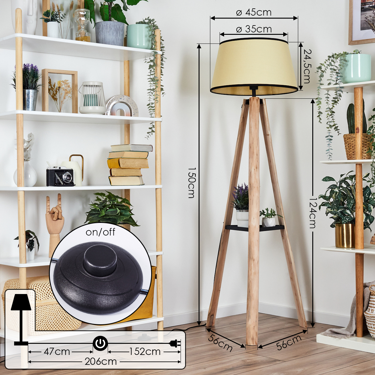 Eine Holz-Stativ-Stehlampe mit beigem Lampenschirm steht neben einem weißen Regal mit Pflanzen und Dekorationen. Ein Fußschalter liegt auf dem Boden.