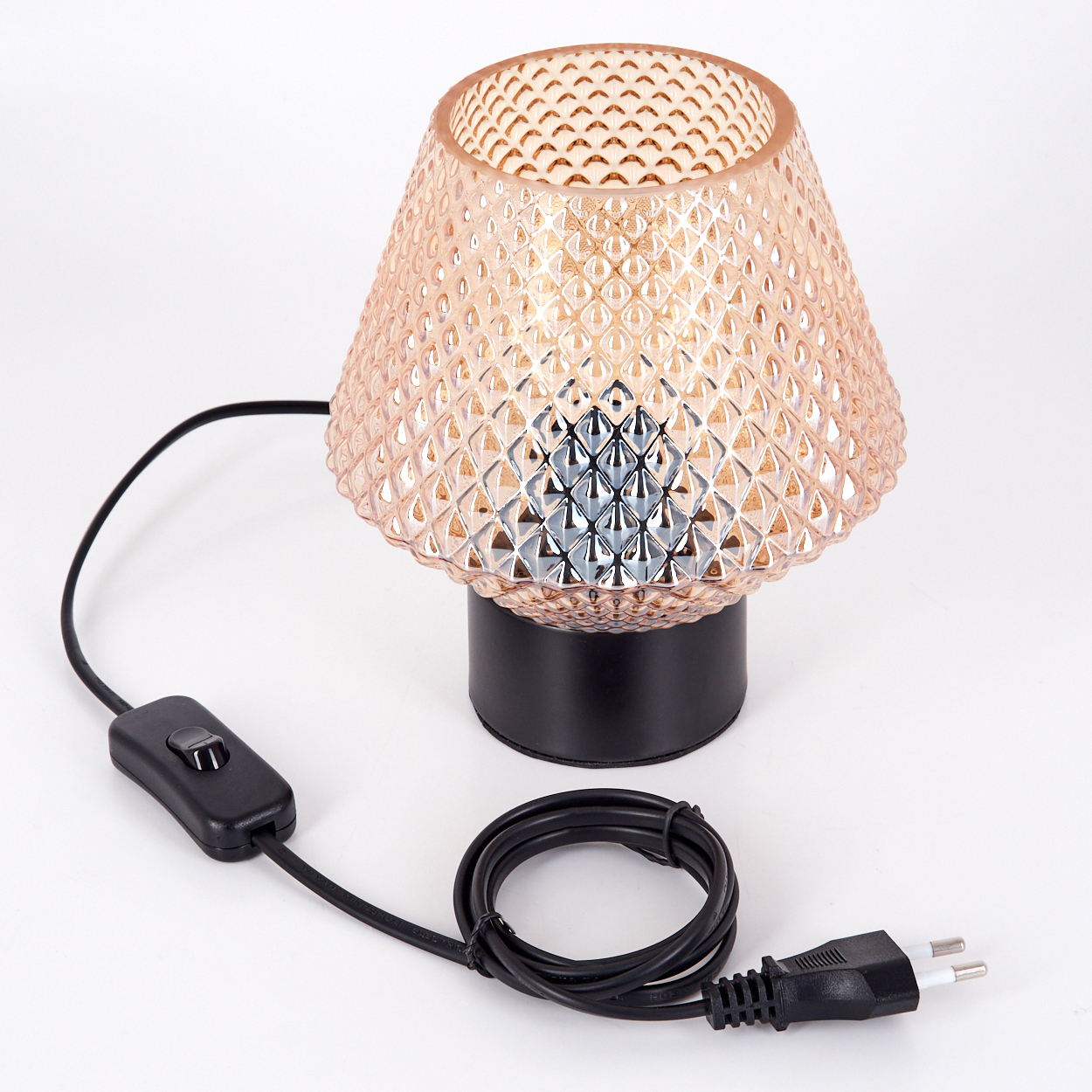 Eine dekorative Tischlampe mit pfirsichfarbenem, gemustertem Schirm, schwarzem Sockel und schwarzem Kabel mit Schalter und Stecker auf weißem Hintergrund.