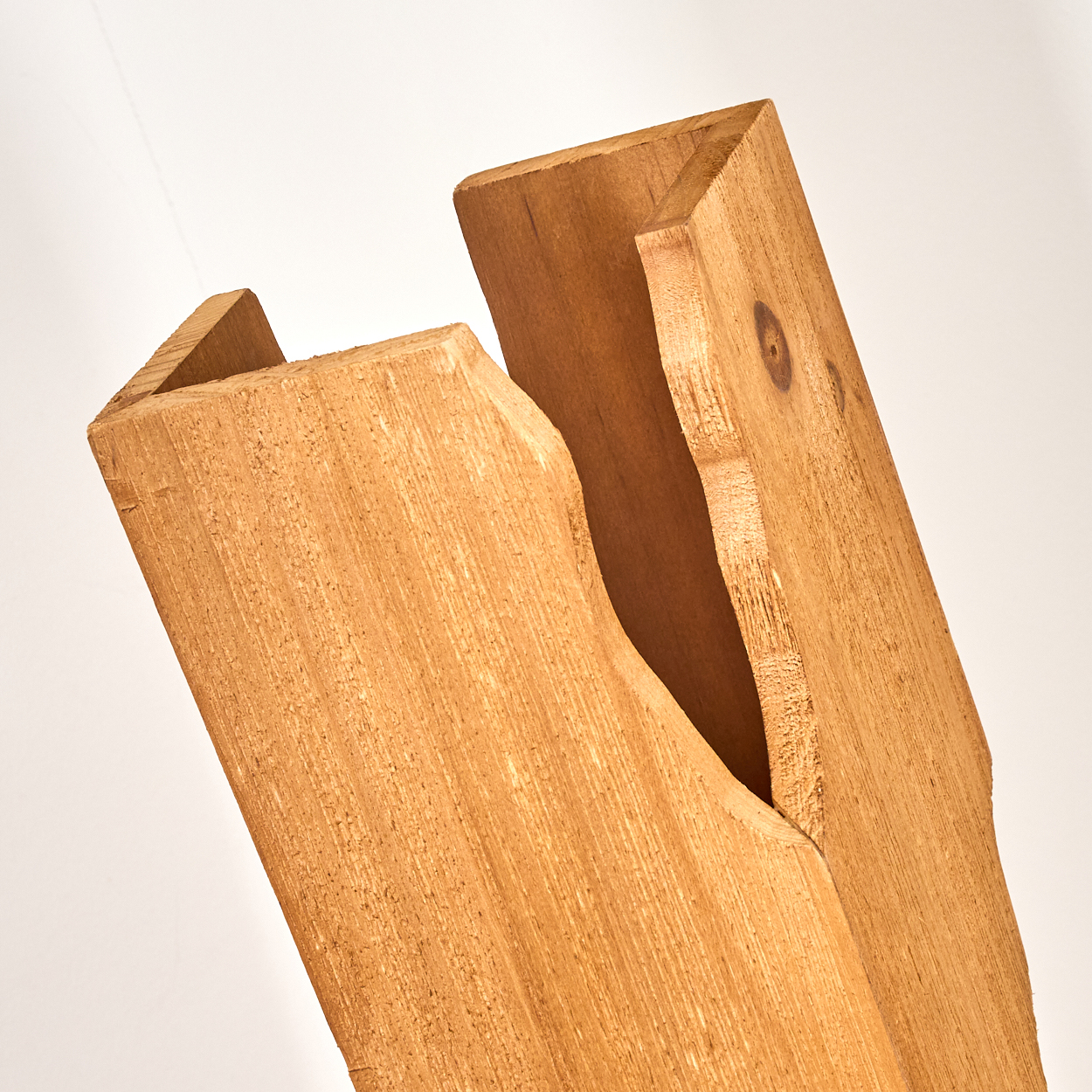 Zwei verwitterte Holzbohlen, eine schräg über der anderen, vor weißem Hintergrund. Das Holz ist hellbraun mit sichtbarer Maserung.