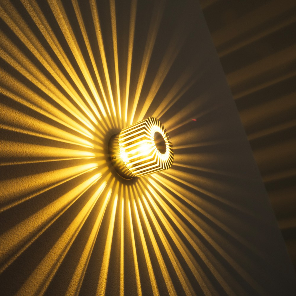 Eine dekorative Wandlampe strahlt Lichtmuster aus. Die Lampe hat ein geometrisches Design mit einer hellen Glühbirne.