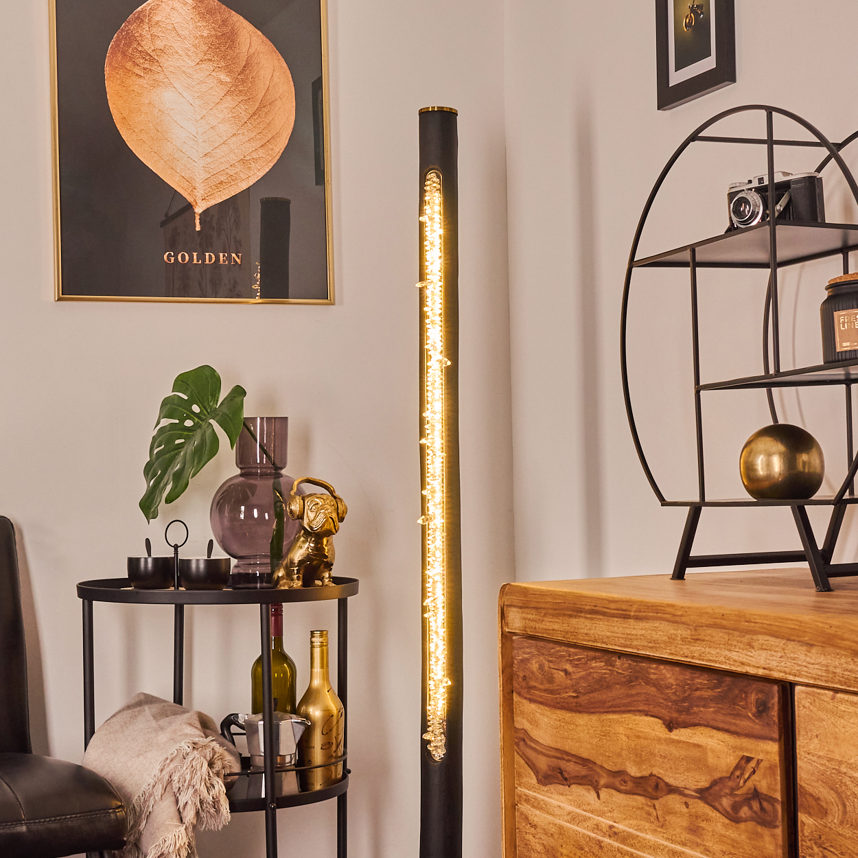 Interieur mit Goldblattkunst, einer hohen Lampe, einem runden Regal mit Gegenständen und einem Holzschrank.