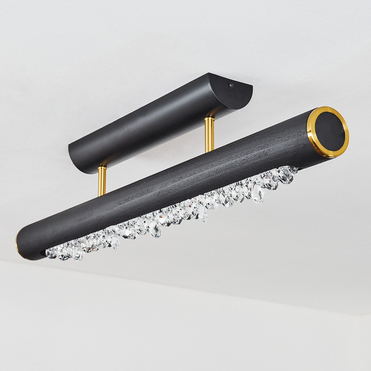 Schwarze und goldene Deckenleuchte mit hängenden Kristallen. Zwei schwarze zylindrische Stäbe, goldene Akzente, weißer Hintergrund.