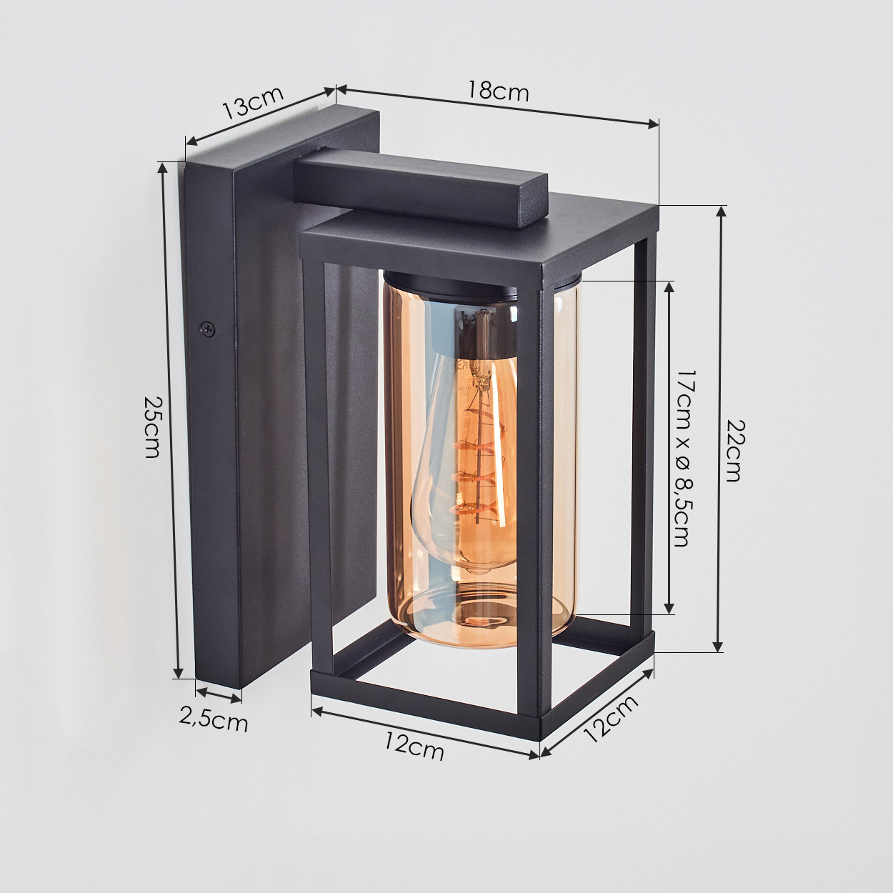 Schwarze Außenwandleuchte mit Maßen. Zylinder aus bernsteinfarbenem Glas mit Glühbirne. Schwarzer Rahmen und Montageplatte. Weißer Hintergrund.