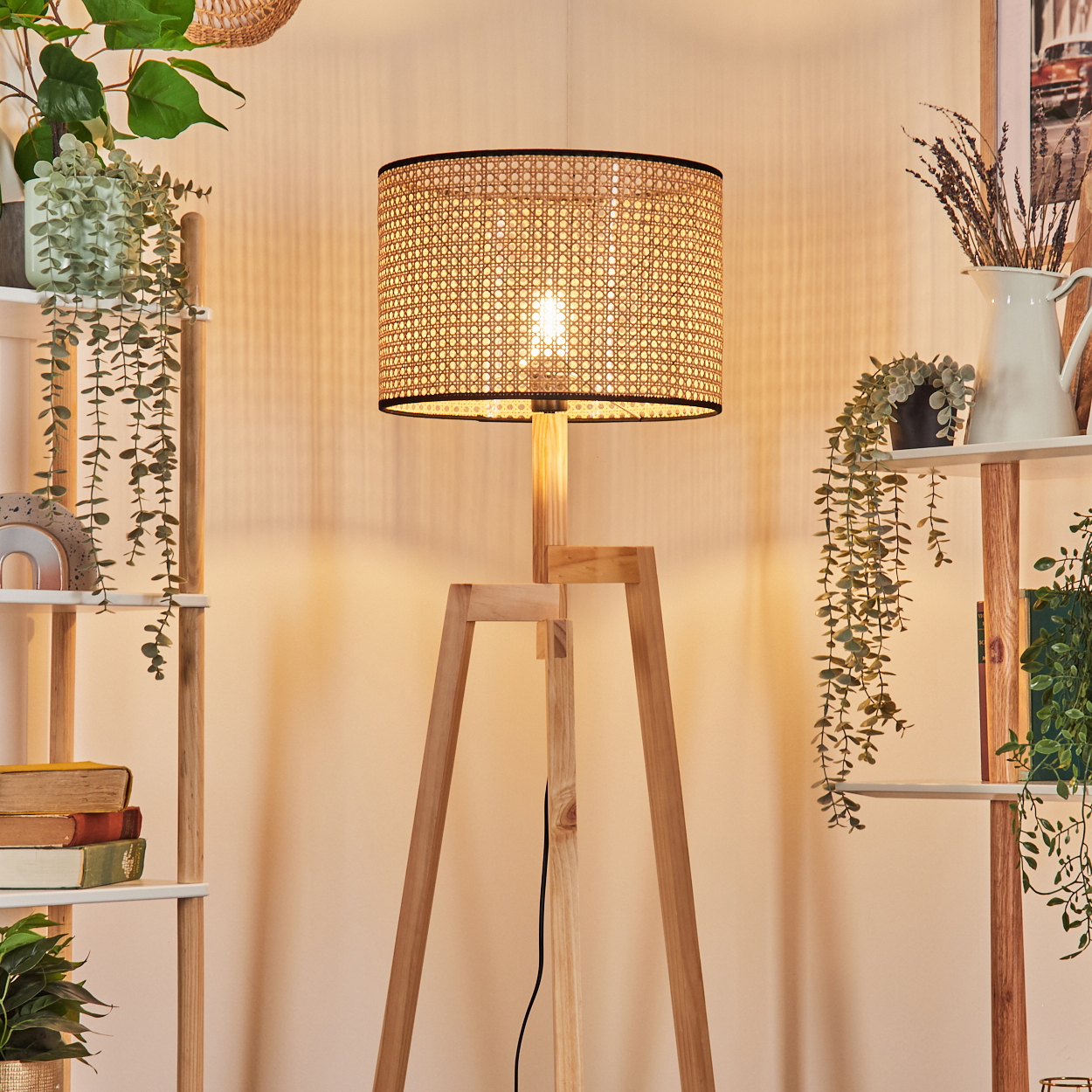 Eine Stehlampe aus Holz mit gewebtem Lampenschirm steht in einem Raum. Regale mit Pflanzen und Büchern stehen auf beiden Seiten.