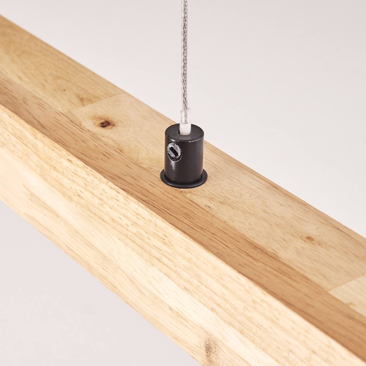 Holzbalken mit schwarzem zylindrischen Befestigungselement und Metallkabel. Der Hintergrund ist weiß.
