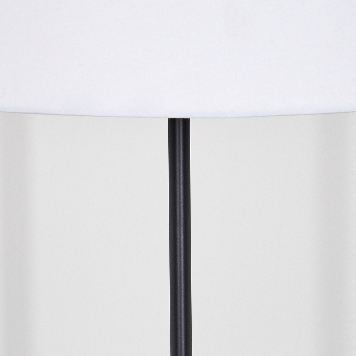 Nahaufnahme einer Lampe. Ein weißer Lampenschirm über einem schwarzen Pfosten vor weißem Hintergrund.