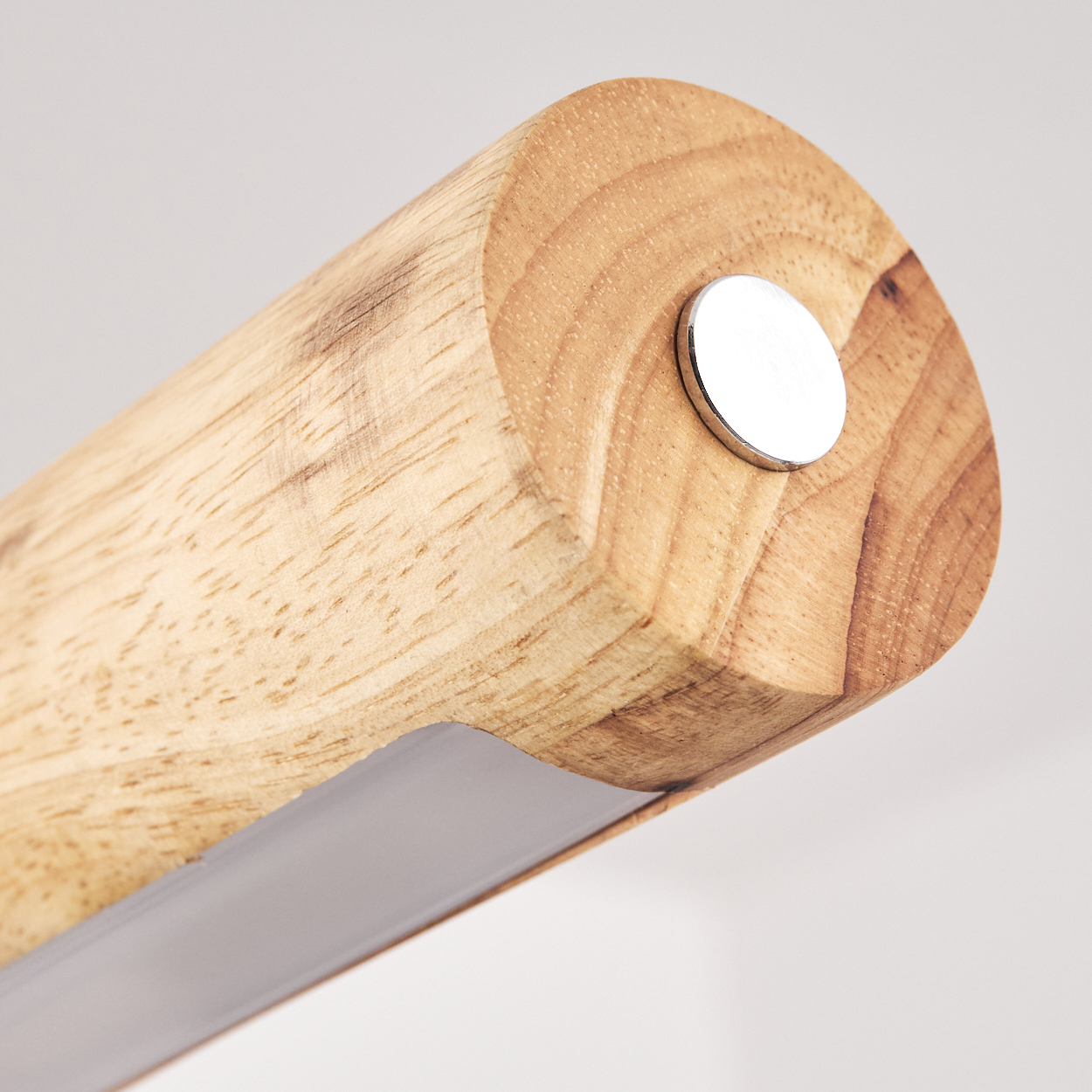 Nahaufnahme einer zylindrischen Holzlampen mit Metallknopf und grauem Lichtstreifen. Der Hintergrund ist weiß.