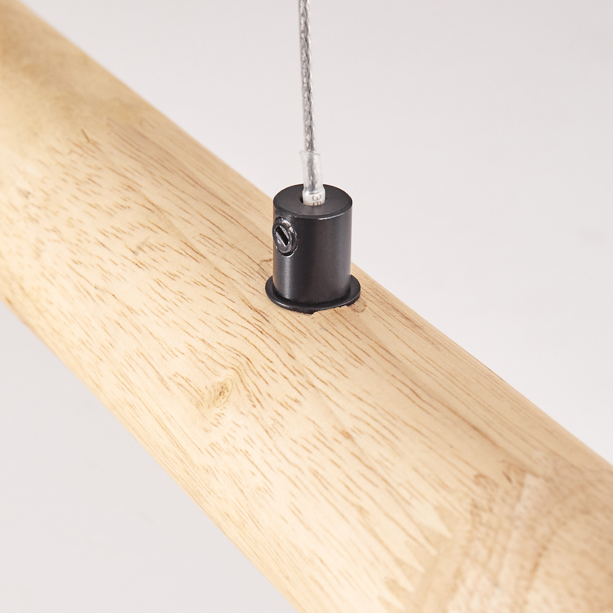Nahaufnahme eines Holzbalkens mit schwarzer zylindrischer Halterung und Hängedraht. Helle Holzmaserung sichtbar.
