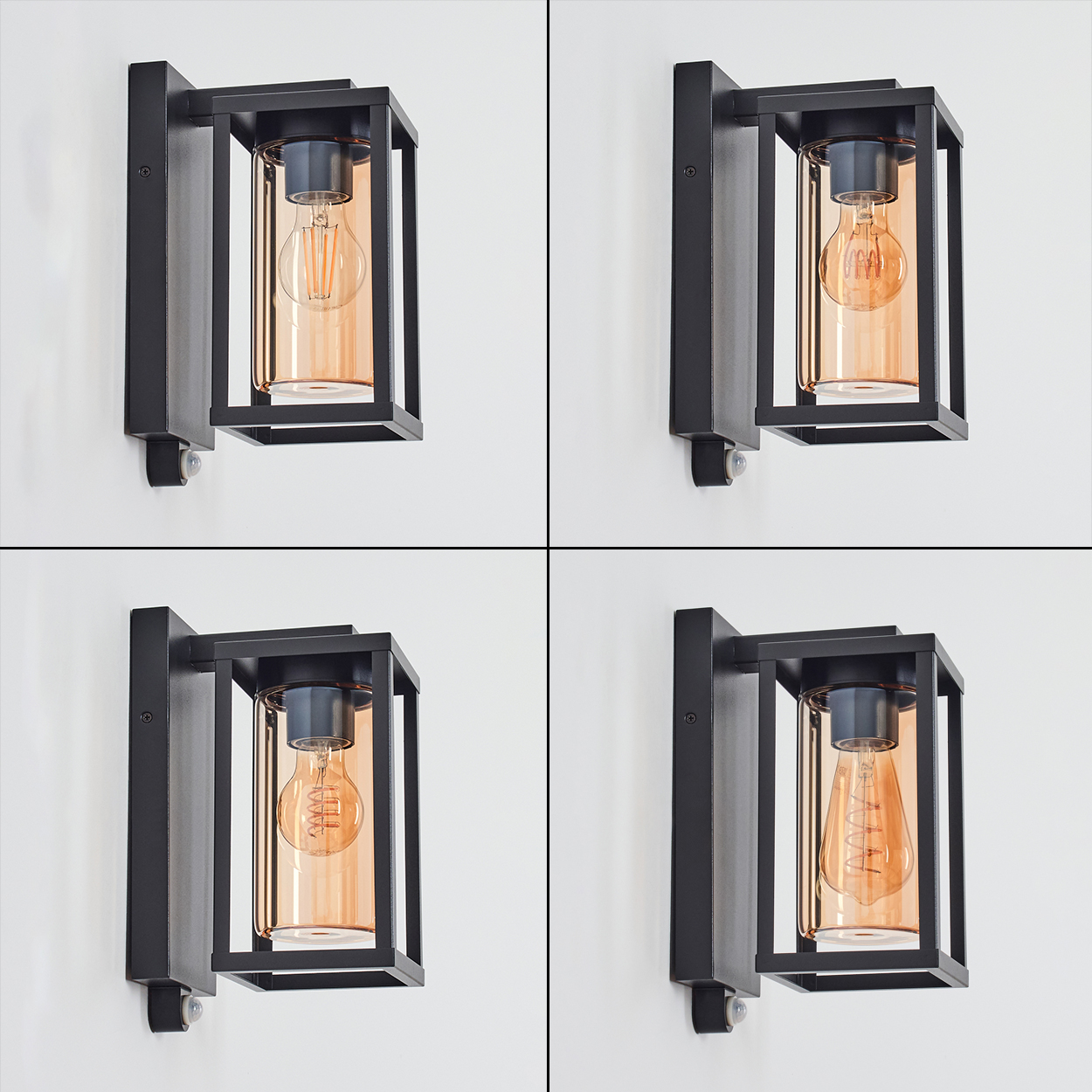 Vier schwarze Wandlampen. Jede Lampe hat einen transparenten, orangefarbenen Glaszylinder mit einer Glühbirne. Sie sind an einer weißen Wand befestigt.