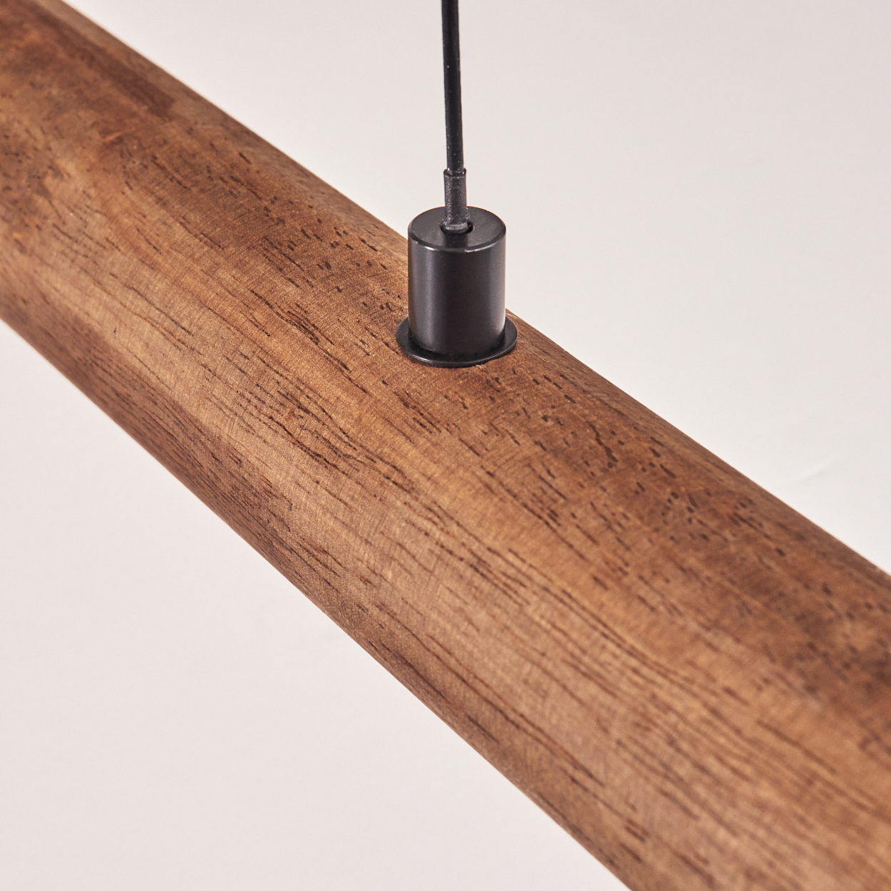 Nahaufnahme eines Holzbalkens. Eine schwarze zylindrische Halterung ist am Holz befestigt, ein schwarzer Draht verläuft nach oben vor weißem Hintergrund.