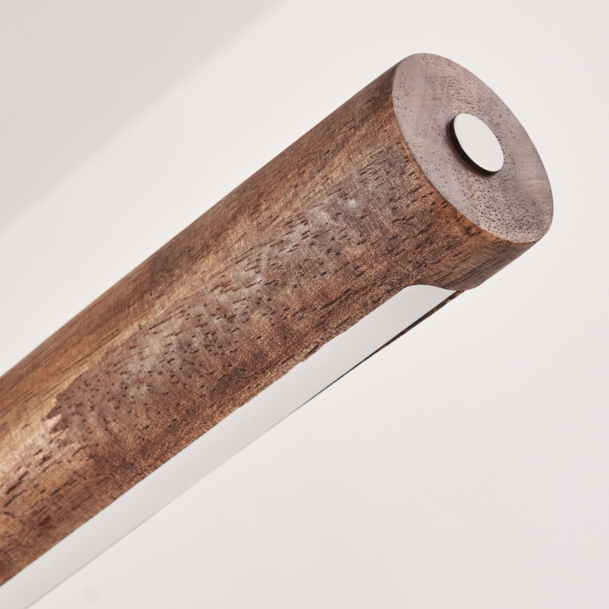 Nahaufnahme eines zylindrischen Holzobjekts mit weißem Streifen, einem Metallkreis auf weißem Hintergrund.