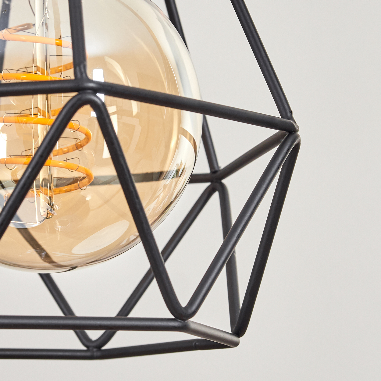 Nahaufnahme einer schwarzen geometrischen Lampe mit Glaskolben. Die Glühbirne hat einen spiralförmigen Glühfaden.