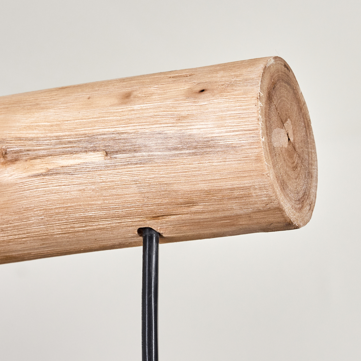 Nahaufnahme eines Holzstamms, der auf einem schwarzen Metallständer befestigt ist. Der Stamm ist hellbraun mit sichtbarer Maserung. Der Hintergrund ist weiß.