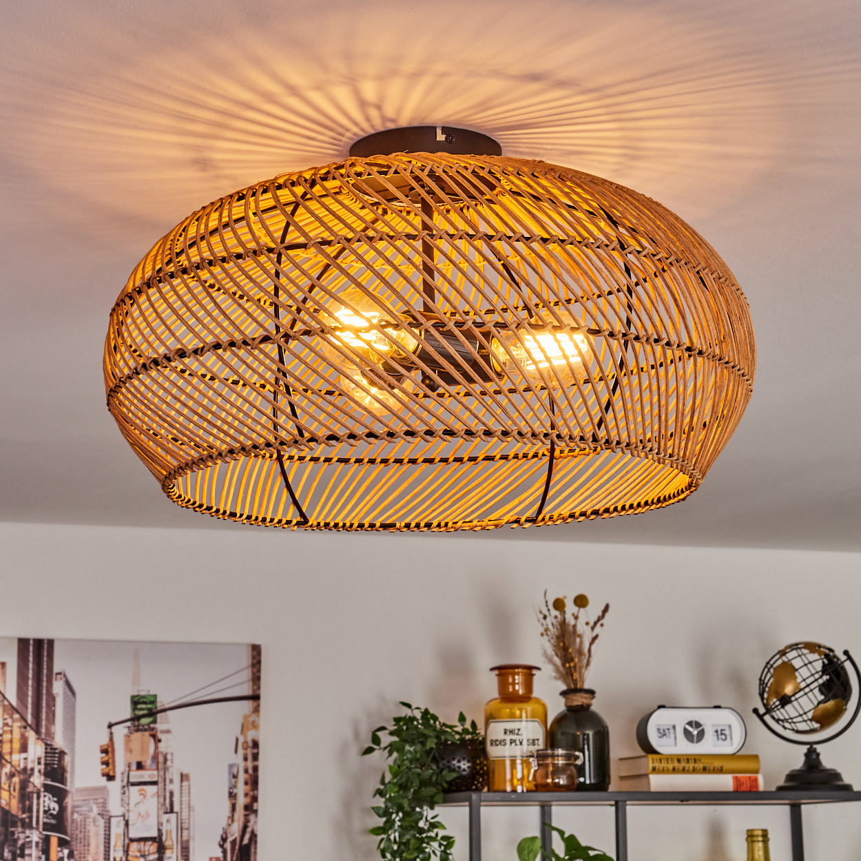 Eine Deckenleuchte aus geflochtenem Rattan beleuchtet einen Raum. Darunter befindet sich ein Regal mit Dekoration, darunter Pflanzen, eine Uhr und ein Globus.