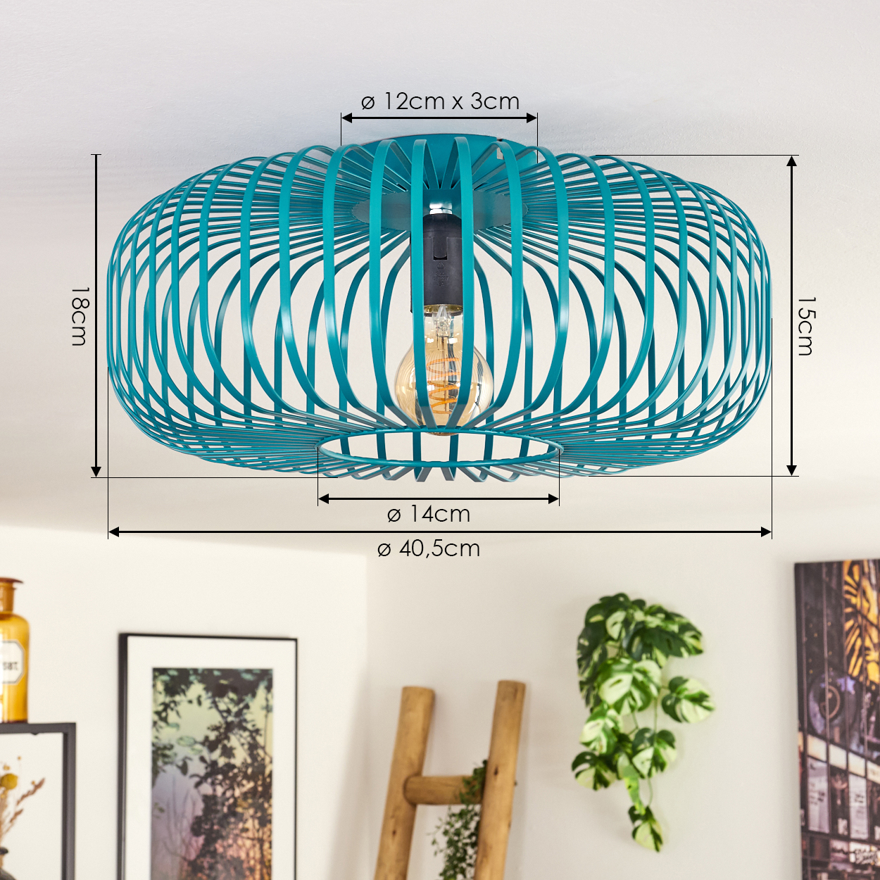 Eine türkisfarbene Deckenlampe mit sichtbarer Glühbirne hängt von der Decke. Im Hintergrund befinden sich eine Leiter, Pflanzen und gerahmte Kunst.