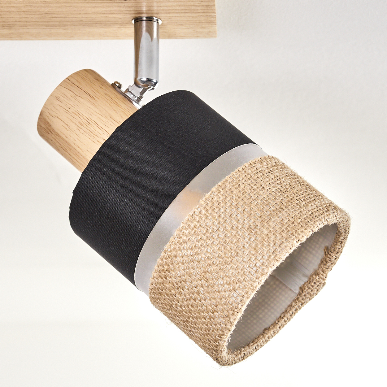 Eine moderne Deckenleuchte mit Holzsockel, schwarzem Stoff und beigem Jute-Schirm. An einer weißen Decke montiert.