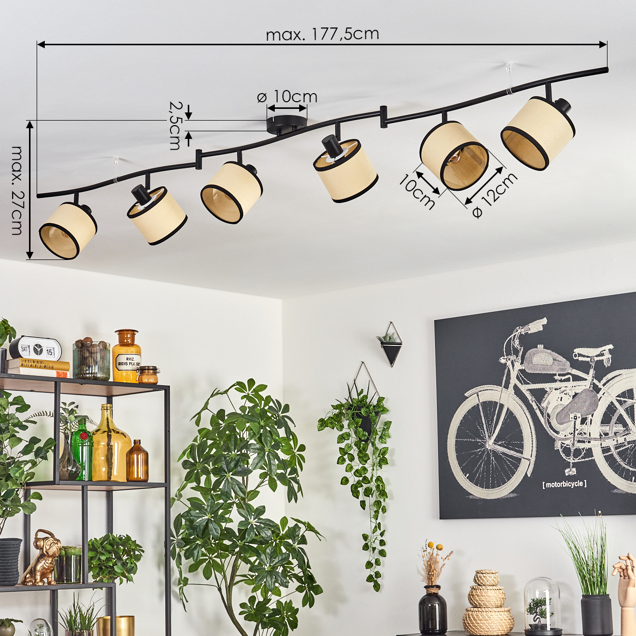 Eine Deckenlampe mit sechs beigefarbenen Lampenschirmen, schwarzem Rahmen. Im Hintergrund Pflanzen, ein Fahrradbild und Dekorationen.