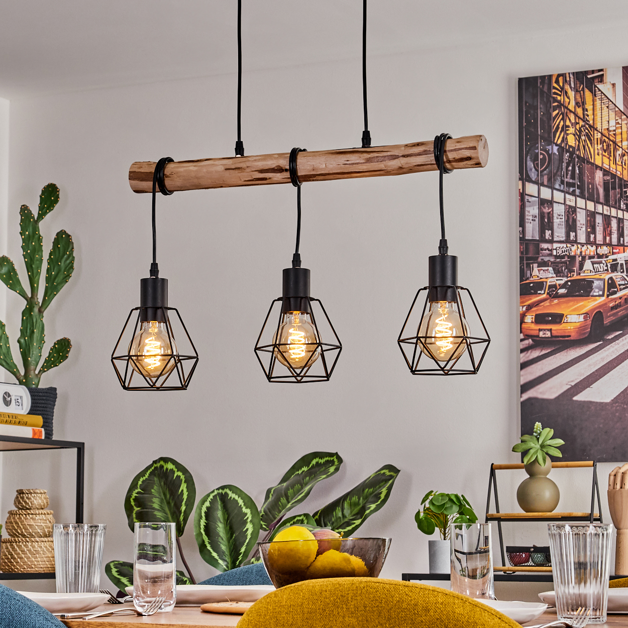 Ein Esszimmer mit Hängelampen, einem gedeckten Tisch und einem New York City Bild an der Wand. Pflanzen und Gläser stehen auf dem Tisch.